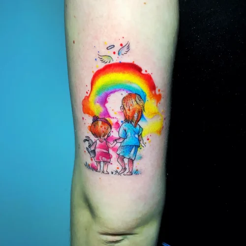 Tatuaje de acuarela en el tríceps de unas niñas y un arcoíris