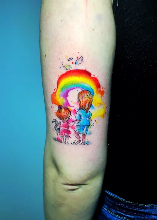 Tatuaje de acuarela en el tríceps de unas niñas y un arcoíris