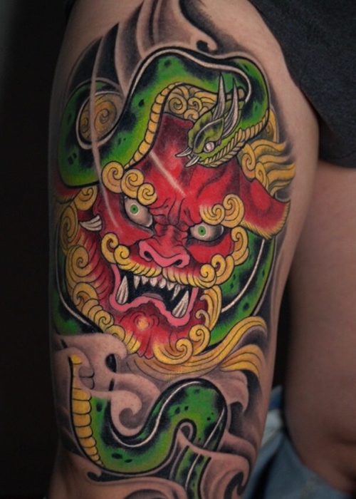 Tatuaje free hand en el muslo de un dragón y una serpiente