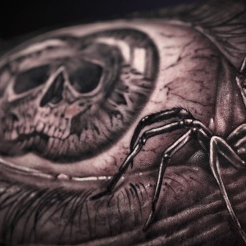 Tatuaje realista de un ojo con una araña